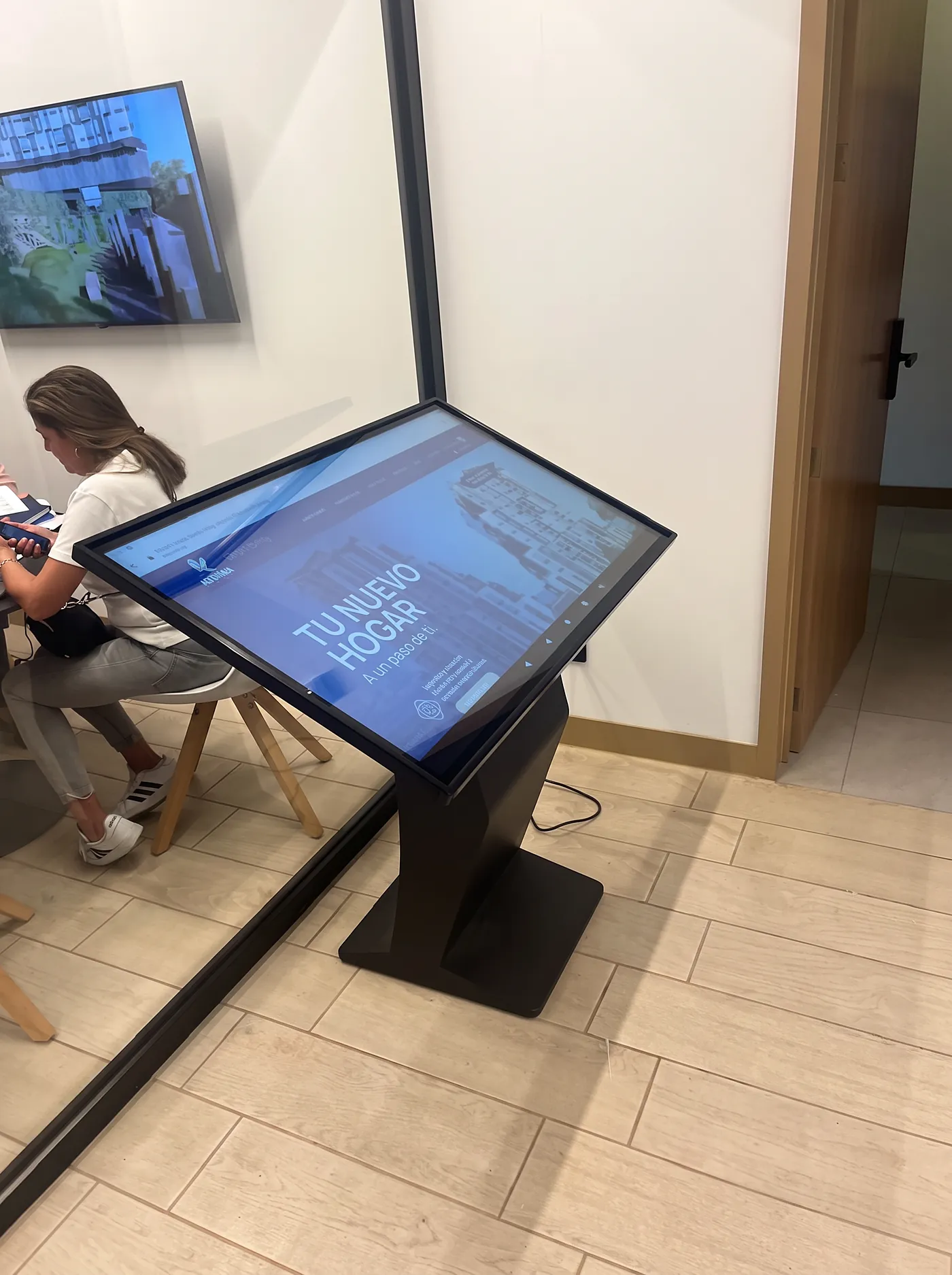 Kiosko táctil de autoservicio en uso en sala de ventas inmobiliaria